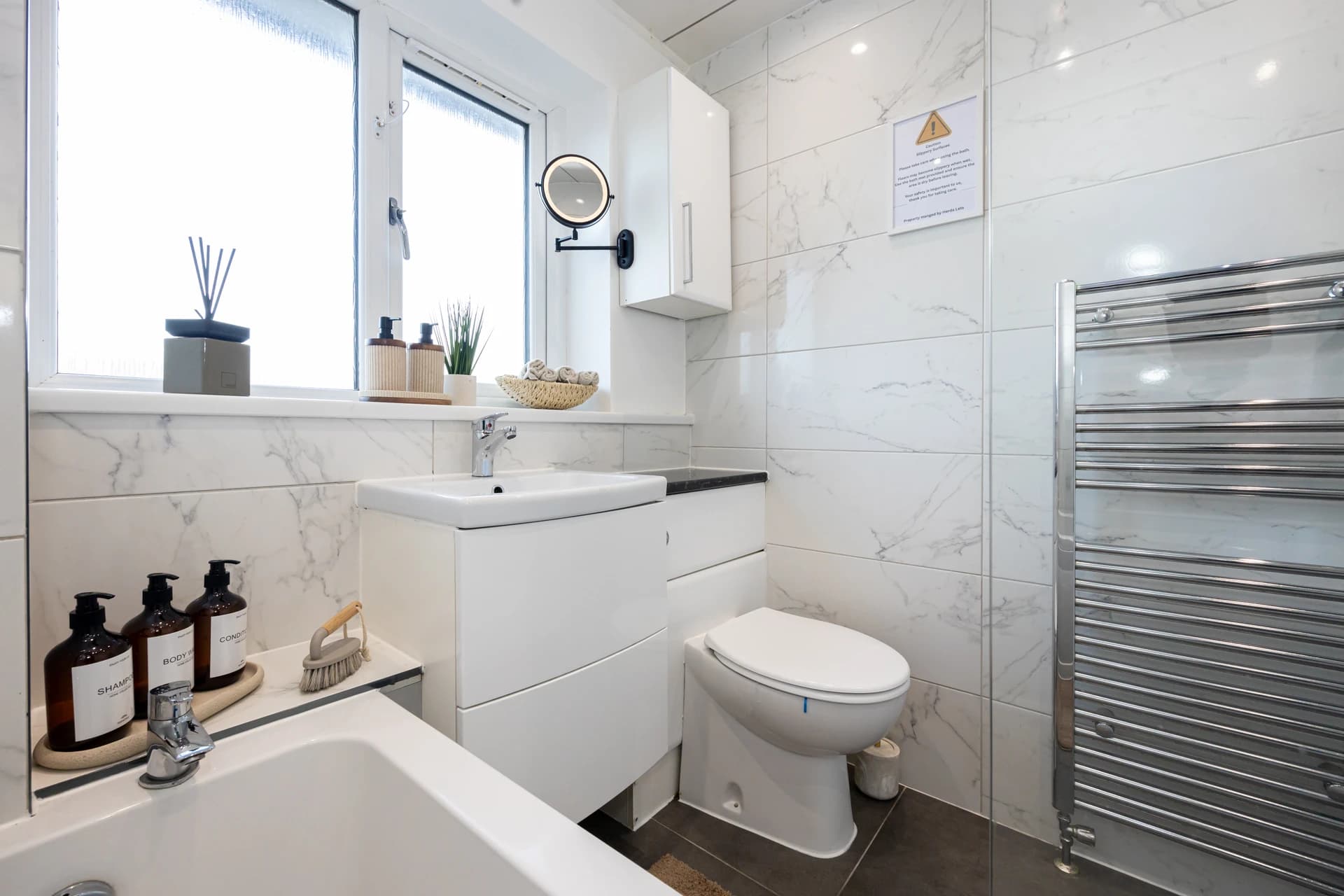 Modern bathroom with bath, basin and heated towel rail at Amberwood Drive
