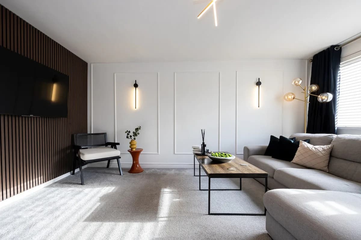 Living room at Amberwood Drive, Wythenshawe, with a grey corner sofa, cushions and a wall-mounted TV