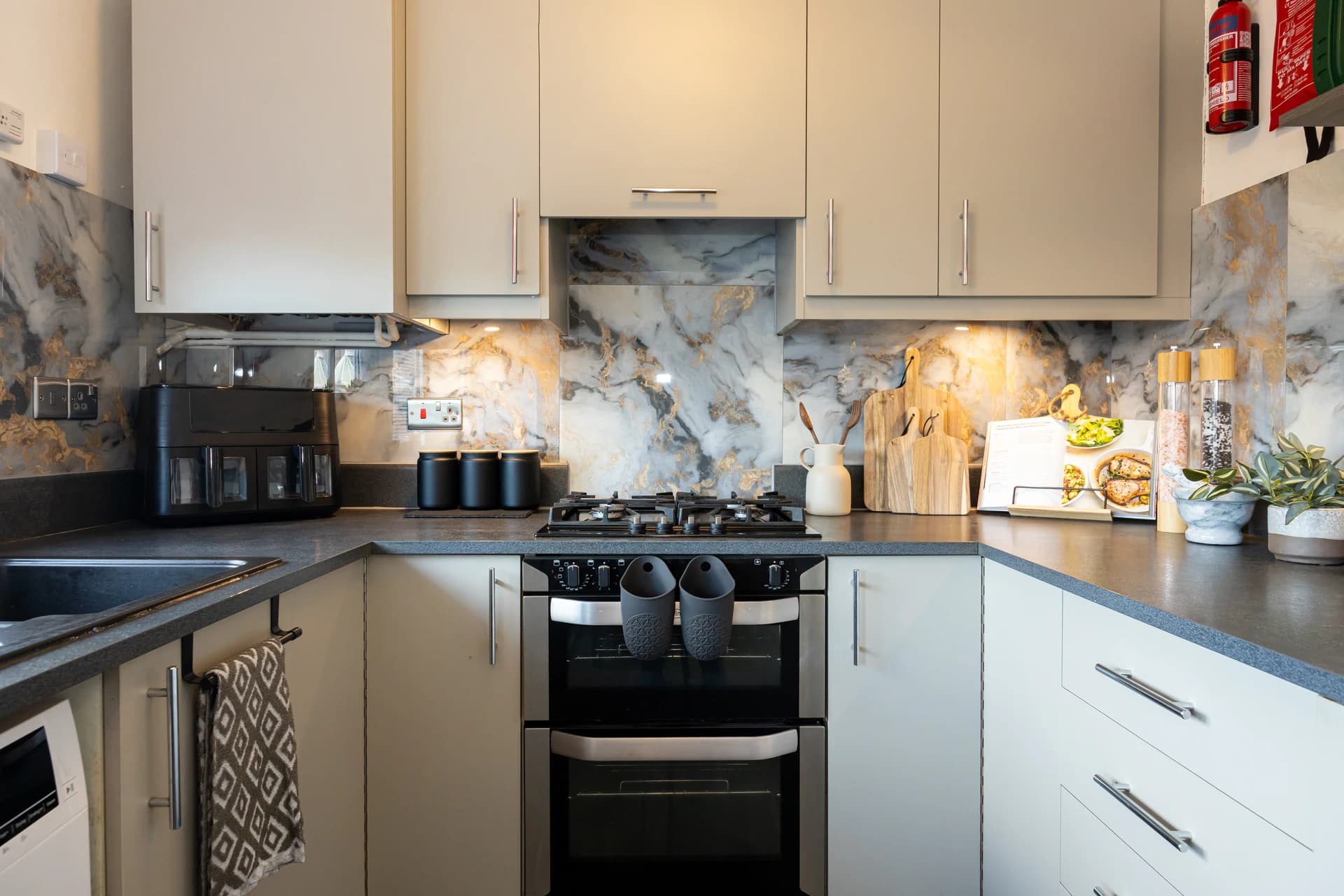 Fully fitted kitchen with oven, hob and marble-effect splashback at Amberwood Drive