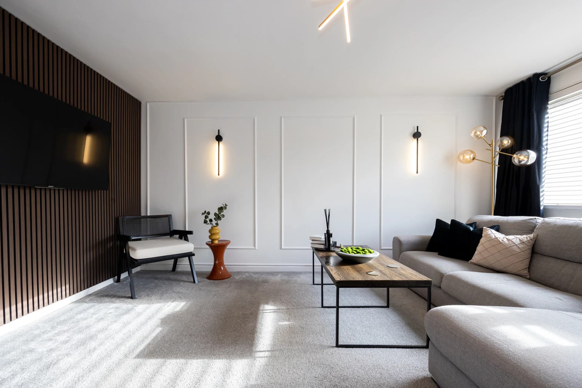 Bright living room with corner sofa, coffee table and wall-mounted TV at Amberwood Drive, Wythenshawe