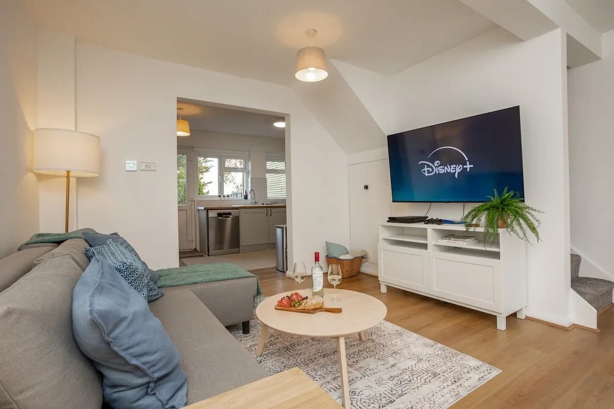 Living room at Doctor's Lane, Melton Mowbray, with a grey sofa, wooden floors and a wall-mounted TV