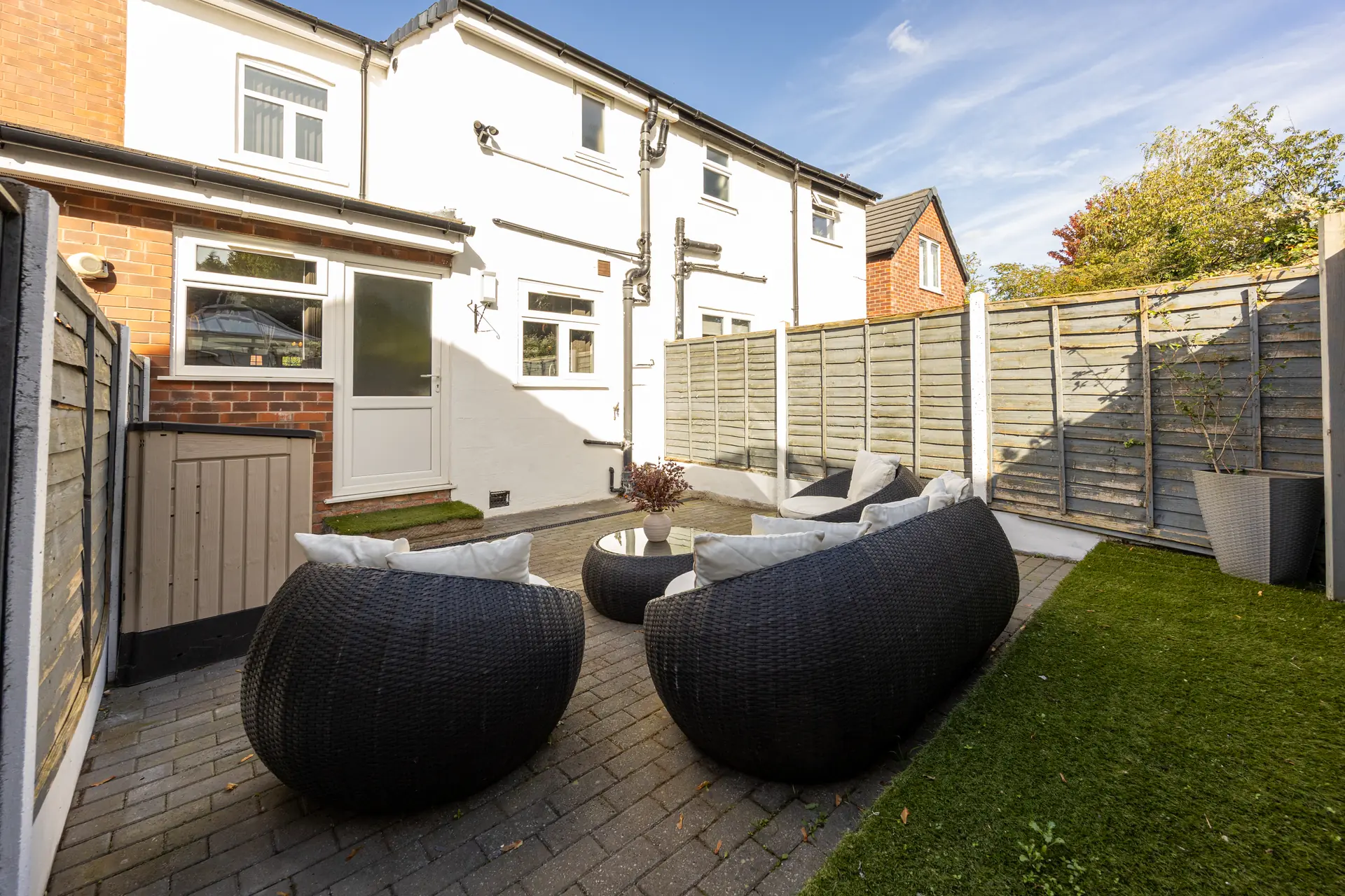 Back garden with lawn and patio seating at Meadow Croft, Wythenshawe