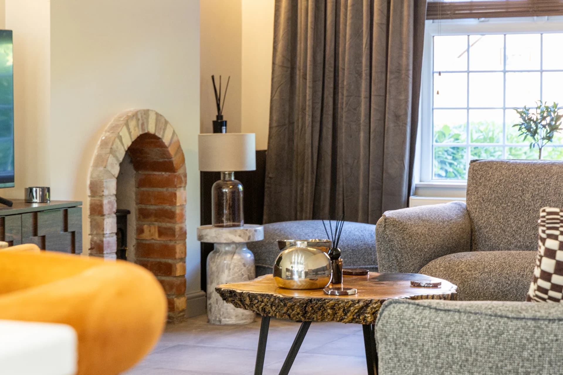 Lounge with brick fireplace and armchairs at Meadow Croft, Wythenshawe