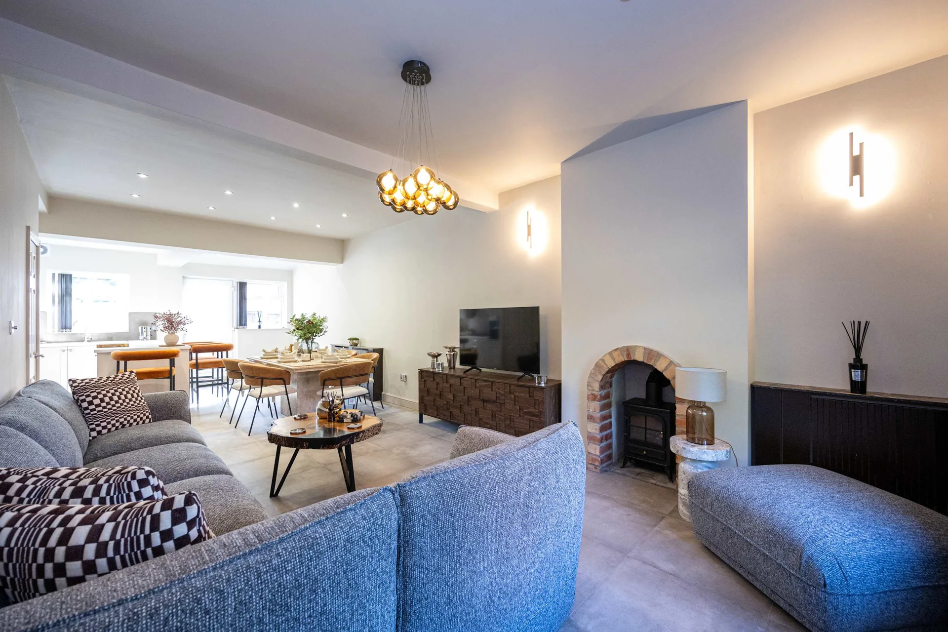 Open-plan living and dining room at Meadow Croft, Wythenshawe, with a corner sofa and a wooden dining table